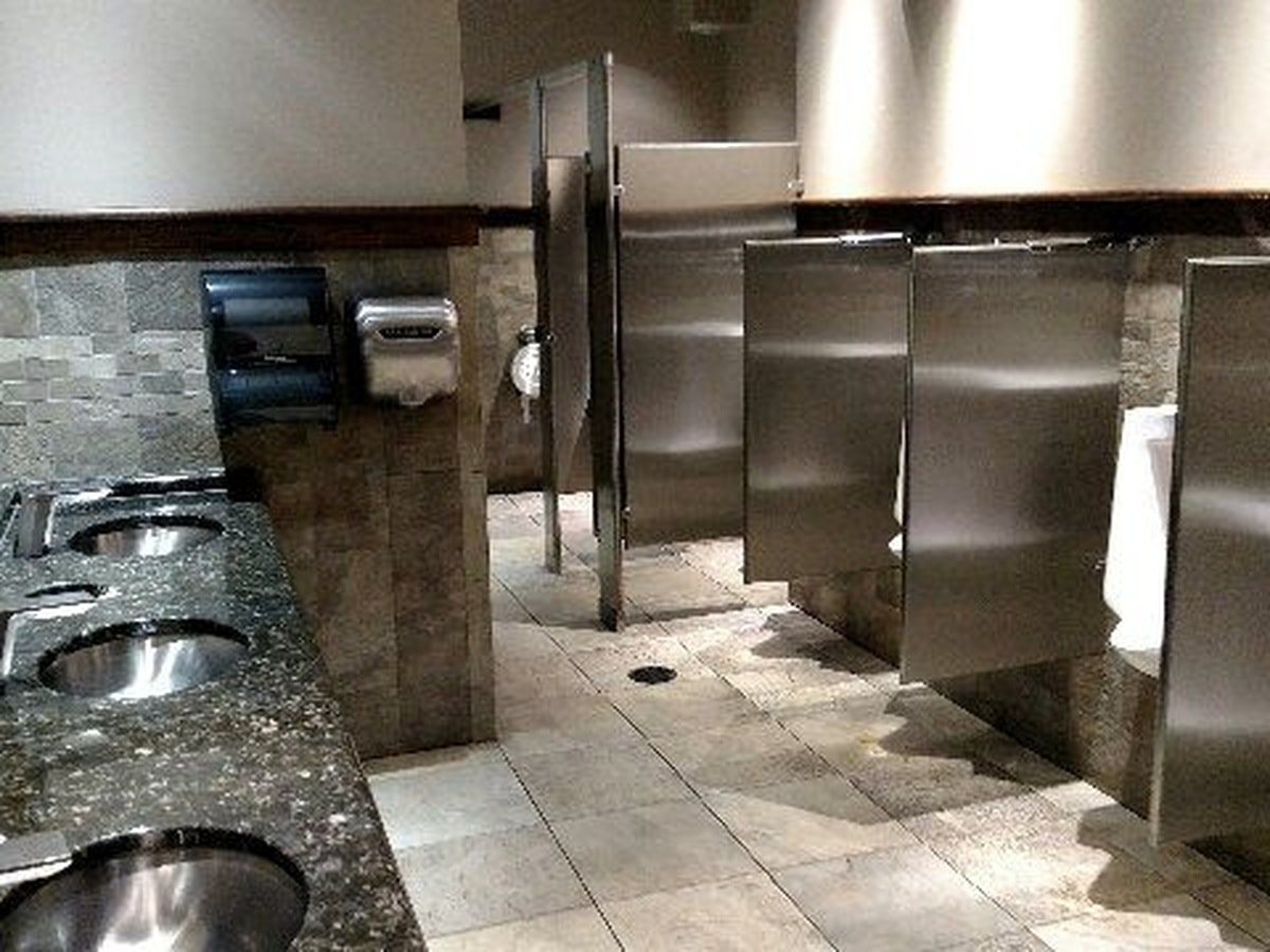 Commercial restroom with granite counters and stainless steel partitions