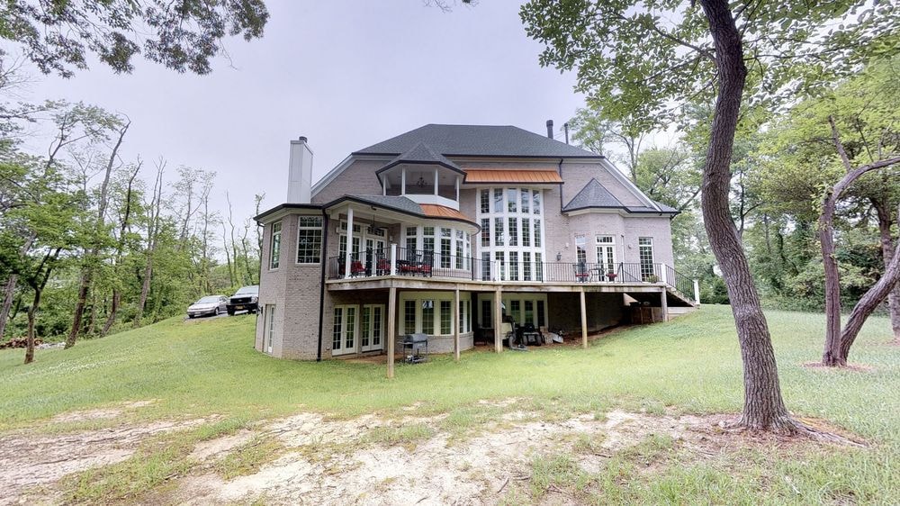 Rear of a brick home with a large wraparound deck addition